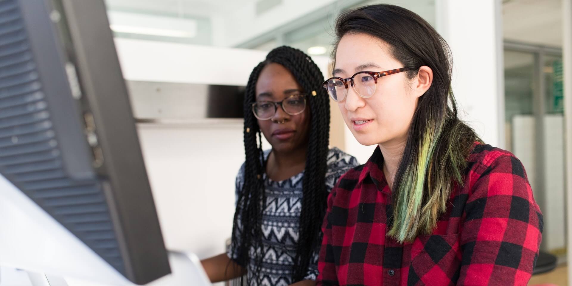 two teachers discuss pre-testing at a computer